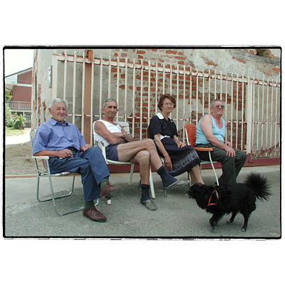 4 anziani che si riposano ed un cagnolino nero che li guarda